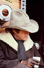 thumbnail link to photograph of Steve as Tom Horn on location, taking coffee break, eyes hidden by hat 